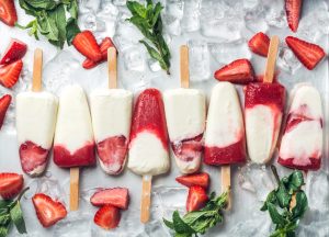 Strawberry yogurt ice cream popsicles with mint over steel tray background. Top view
